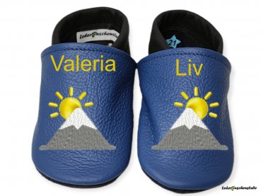Designbeispiel Lederpuschen jeansblau-schwarz mit Stickerei Berg Sonne (weiß-steingrau-gelb) mit beiderseits Namen (gelb)